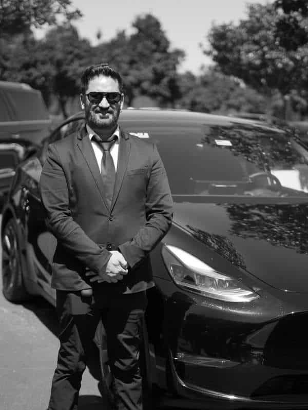 Professional chauffeur standing beside a black vehicle